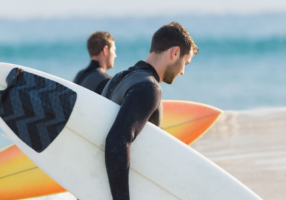 Men holding surfboards heading towards the sea