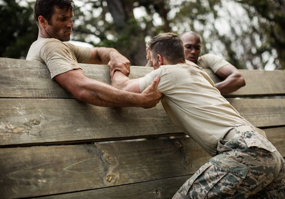 Men dressed in army clothes completing an obstacle course 