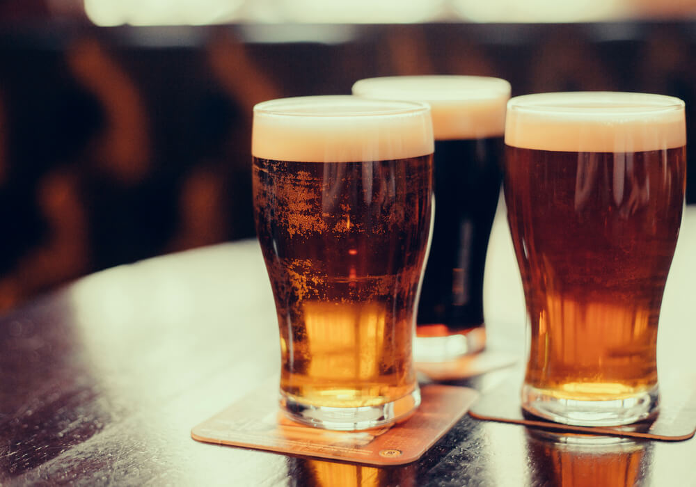 three pints of beer on a table in a pub