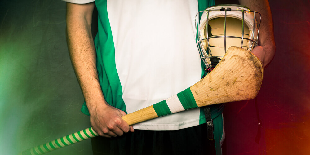 Irish Hurling player's midsection holding hurling stick and helmet 