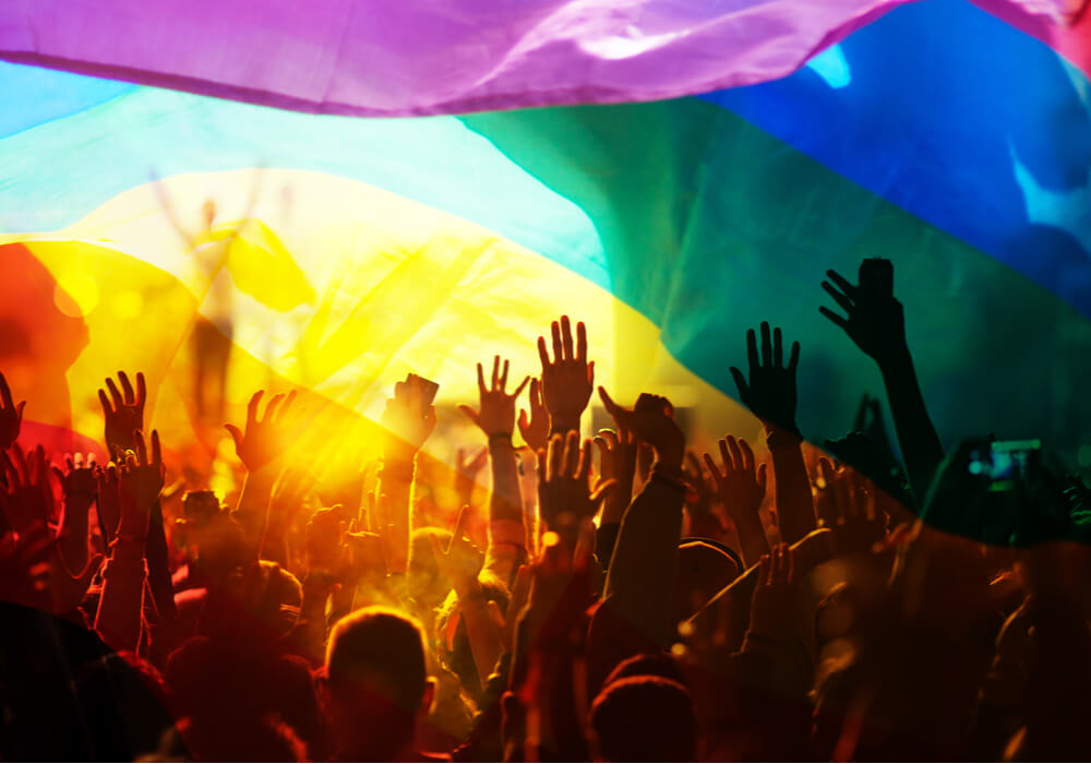 People celebrating Pride with rainbow coloured flag above