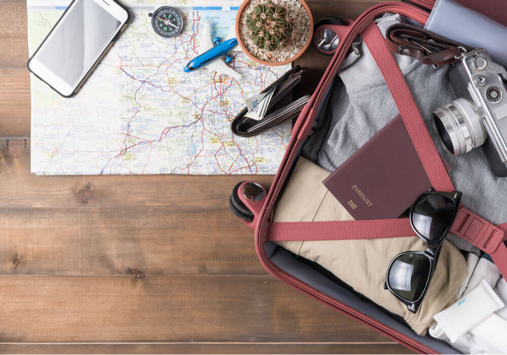 Open suitcase packed for a stag weekend on top of a map